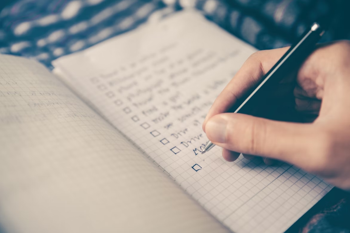 A person writing down a checklist in a notebook